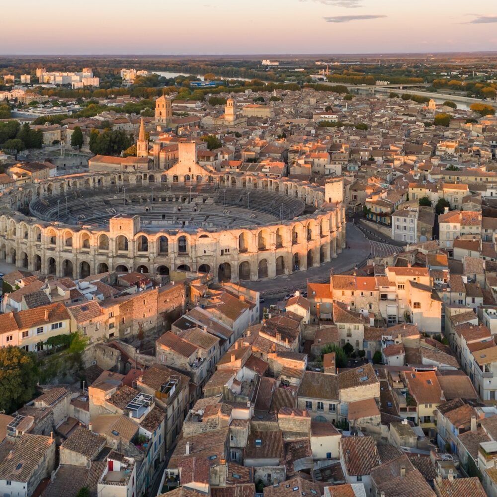 Cityscape of Arles at sunrise, southern France. HIstoric buildings, Arles Amphitheatre and Rhone river visible from above. Aerial view of the Arles city, South of France